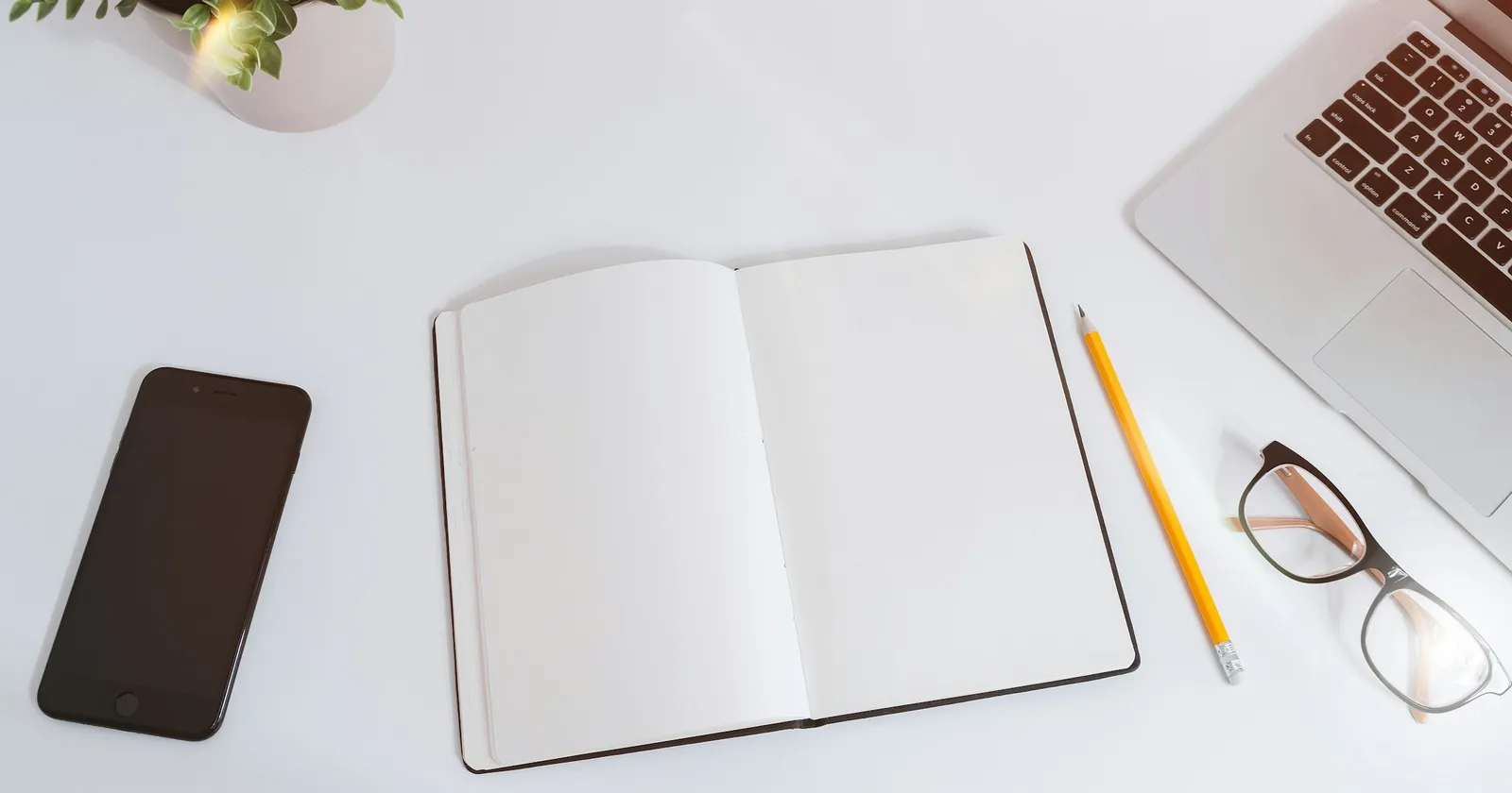 Computadora portátil, teléfono y cuaderno sobre una mesa de trabajo